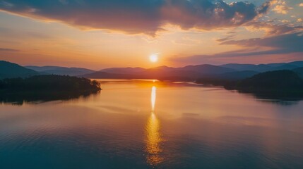 Obraz premium Create an aerial view of a calm lake with a beautiful sunrise or sunset in the background. Capture the serene and peaceful atmosphere, showcasing the reflection of the sunrise or sunset on the water. 