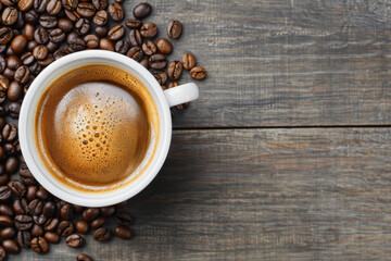 A steaming cup of freshly brewed coffee surrounded by scattered coffee beans on a rustic wooden table.