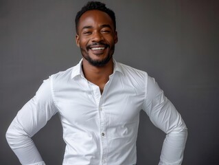 Fototapeta premium A smiling man in a white shirt poses confidently against a neutral background, radiating positivity and professionalism.