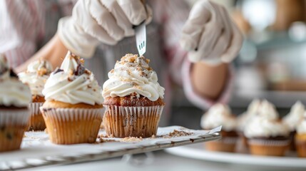 A professional baker artfully decorating cupcakes with white icing and sprinkled toppings, highlighting precision and creativity in a bustling bakery kitchen setting.