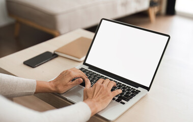 Young woman holding a laptop with a blank white screen on the table. Work space in your home living room or home office