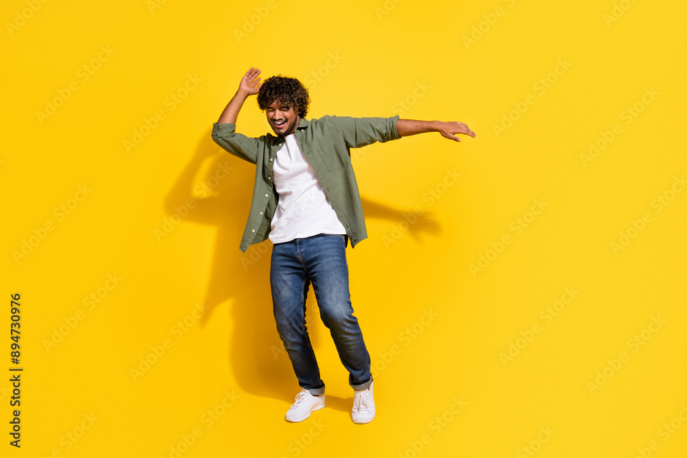 Poster Portrait photo young dj funny mexican guy in khaki shirt dancing rhythm of the night isolated on yellow color background