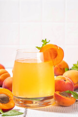 Apricot mojito or lemonade cold fruit drink, summer iced fruit juice non-alcohol mocktail with mint and lemon, on white wooden table
