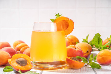Apricot mojito or lemonade cold fruit drink, summer iced fruit juice non-alcohol mocktail with mint and lemon, on white wooden table
