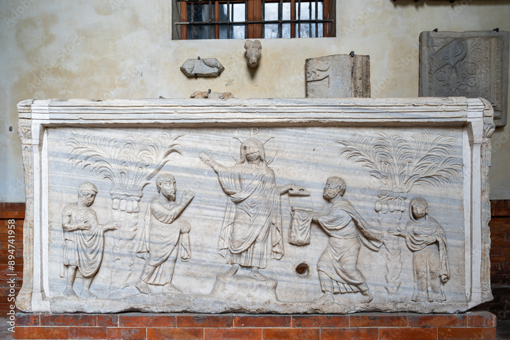 Wall mural Ancient christian sarcophagus in marble ornated with carved sculptures of Christ performing a miracle to a group of people