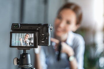 Camera recording video blog of asian woman influencer showing smart watch at office, cafe. Technology female blogger reviewing about new gadget while recording video for Youtube channel