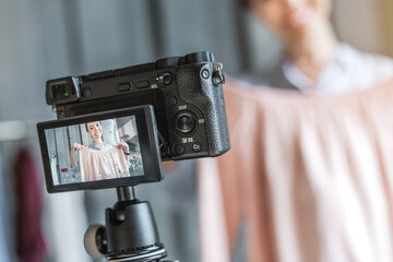 Close up of female fashion blogger showing cloth while recording vlog and live streaming with camera at her shop showroom. SME freelance business online concept. Video marketing production