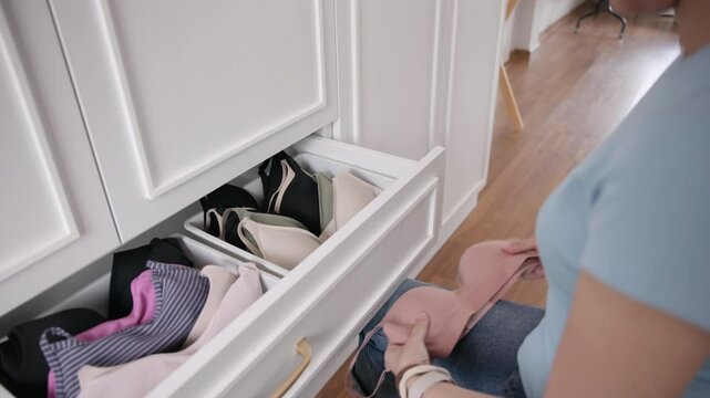 Young adult woman asia people arrange stack undies manage used old bra neat basket box clean house closet shelf eco care. Happy asian go green wife home chores zero waste reduce fabric issue