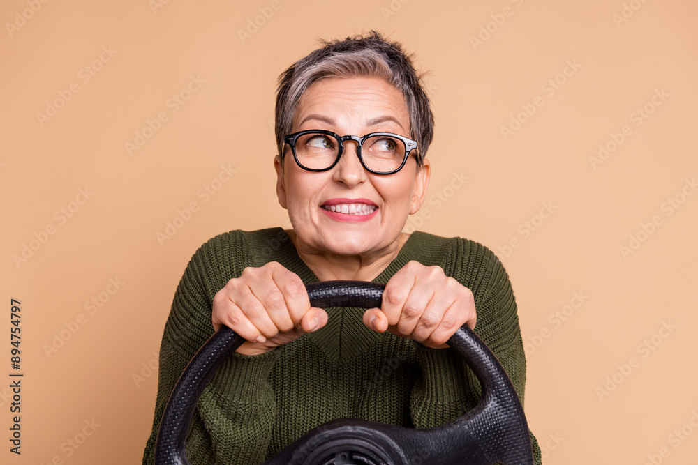 Sticker Photo of charming lovely senior woman wear green stylish clothes drive car look empty space isolated on beige color background