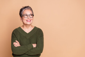 Photo of positive woman with short hair dressed sweater hold arms crossed look at sale empty space isolated on beige color background