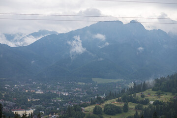 Mountain range. Wildlife in the mountains. White clouds over the peaks of rocky mountains. High mountain peaks. Tatra Mountains. There is a city in the gorge. A settlement at the foot of the mountain.