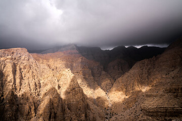 sun peaking through stormy clouds in UAE mountains