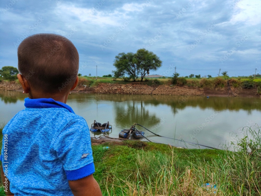 Wall mural a boy standing near to the river