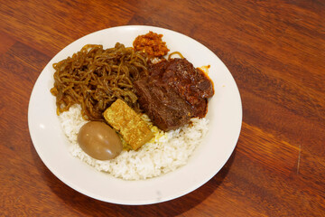 Nasi campur tambak bayan, featuring a bed of rice, topped with savory rendang, a hard-boiled egg.