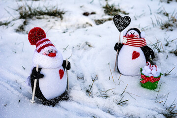 Winter composition: two toy penguins in knitted hats and scarves met on a walk. 
