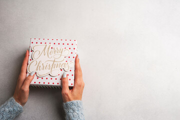 Beautiful female hands holding a Christmas gift box on a Light background