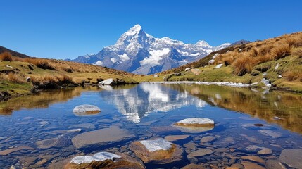 Fototapeta premium Impressive snowy mountains tower over a crystal-clear lake, their reflection creating a picture-perfect mirror image, surrounded by rugged terrain and sparse vegetation.