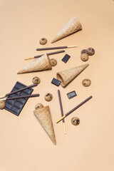 Waffle cones, chocolate sticks, and cookies on beige background.