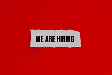 We are hiring message written on ripped torn paper piece with red background. Conceptual we are hiring symbol. Copy space.