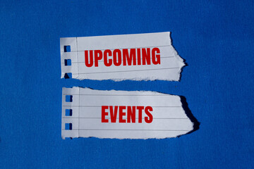 Upcoming events message written on ripped torn paper pieces with blue background. Conceptual upcoming events symbol. Copy space.