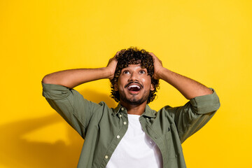 Portrait photo of young latin guy in khaki shirt surprised black friday low prices brand offers isolated on yellow color background