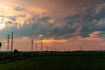 夕焼けに染まる雲と送電鉄塔のシルエット
