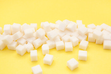 White sugar cubes on yellow background, sweet food ingredient