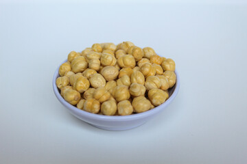 Chickpeas in small white bowl, isolated on white background