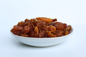 Raisins in small white plate, isolated on white background