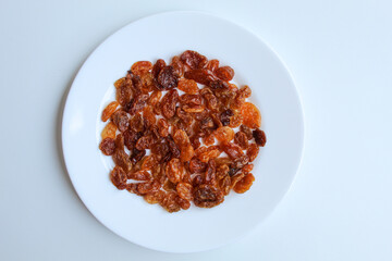 Raisins on white plate, flat lay or top view