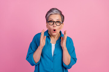 Photo portrait of lovely pensioner lady raise hands shocked dressed stylish blue garment isolated on pink color background