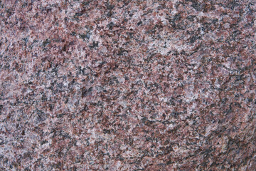 Large granite stone boulder texture background. Red granite old boulder with noise and grain in grunge style. Top view. Natural raw sheer cliff texture. Copy space.