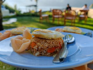 Fried rice with fried egg, sausage, cucumber and crackers. Served in the morning, selected focus blurred background