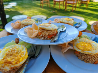 Fried rice with fried egg, sausage, cucumber and crackers. Served in the morning, selected focus blurred background