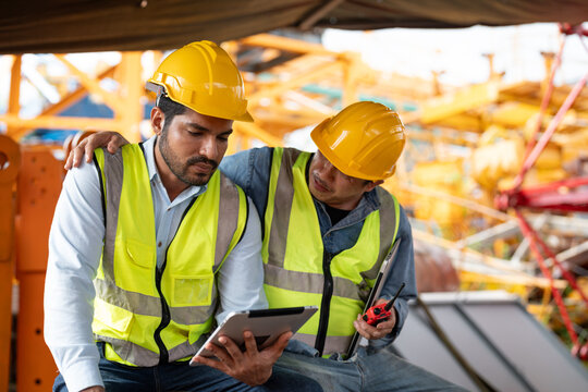 Asian man worker held tablet feeling sad and upset while sitting at construction site. Senior coworker wrapped around his shoulder and consoled him.