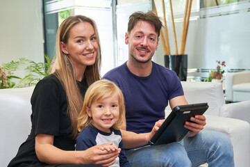 family sitting on a dentist's couch filling in personal data on a tablet