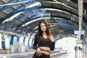Fototapeta premium Young woman standing on a metro station platform and waiting for a metro train. People travel in public transport concept.