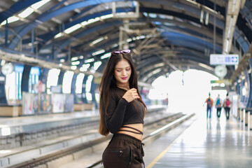 Obraz premium Young woman standing on a metro station platform and waiting for a metro train. People travel in public transport concept.
