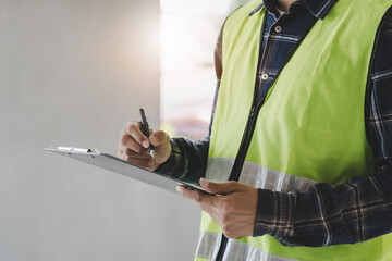 Asian inspector checking structure of new property and taking note in the clipboard for review and...