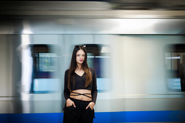 Young woman standing on a metro station platform and waiting for a metro train. People travel in public transport concept.