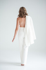 young blonde woman in white jacket and bra on grey background