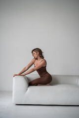 Obraz premium young beautiful woman in beige dress on white background posing in studio