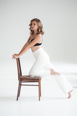 young beautiful woman in formal clothes posing on a chair in studio