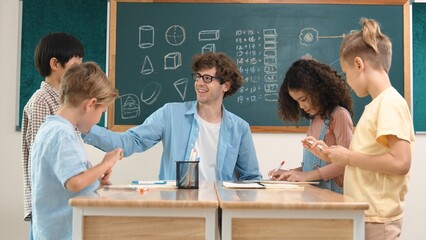 Smart teacher explain idea while diverse children drawing mind map while group of diverse student working together to do class work. Attractive instructor teaching and talking about working. Pedagogy.