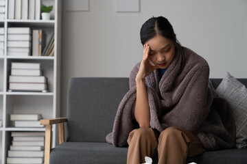 Obraz premium A photograph depicting a female individual in a state of discomfort seated upon a sofa within a residential setting.