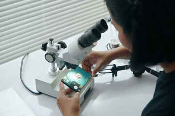 Master examining disk under microscope while repairing drone at table