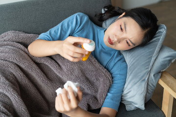 A photograph depicting a female individual in a state of discomfort seated upon a sofa within a residential setting.