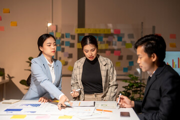 Three people are sitting at a table with a whiteboard in front of them