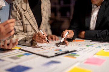 Three people are sitting at a table with papers and pens