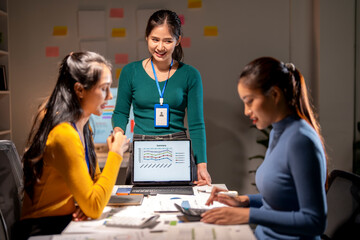 Three women are sitting at a table with a laptop open in front of them